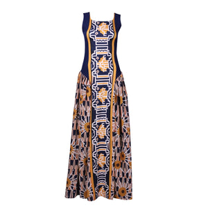 A bold geometric Tshwane print maxi dress featuring a fitted sleeveless bodice in navy with mustard accents and a flared skirt with intricate patterns in earthy tones. The dress combines structured elegance with flowing gathers, perfect for a statement look.