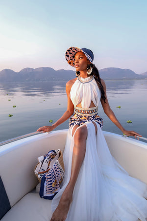 A lady wearing a stunning Tshwane geometric-patterned print dress with a dramatic white tulle skirt, on a boat ride in Hartebeespoort Dam.